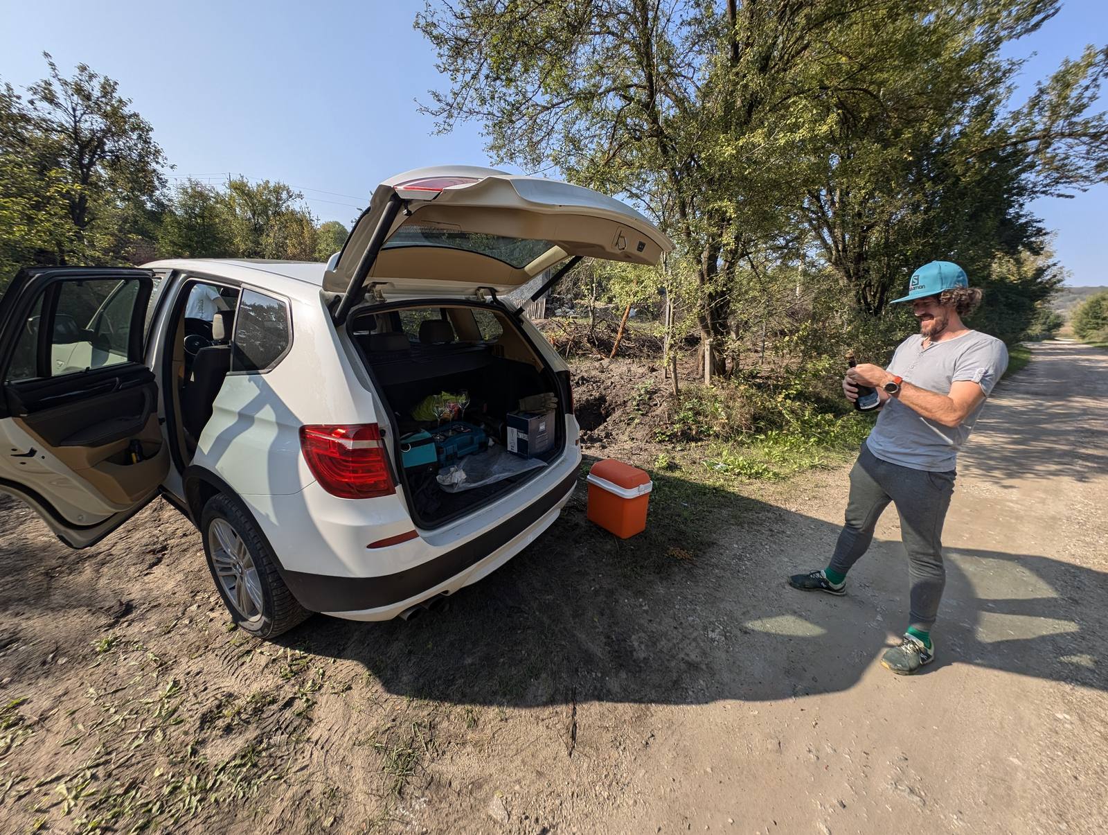 The X3 with the tailgate open, tools and a cooler, in the field