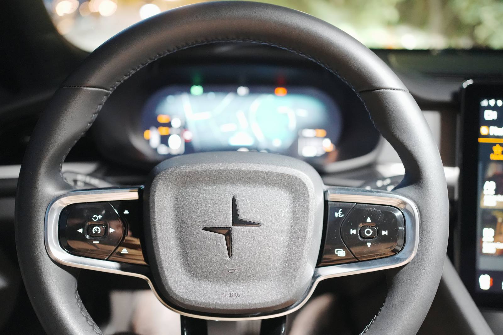 The steering wheel with its two clusters of physical buttons: cruise control on the left, music and voice control on the right; behind, the driver display with the map